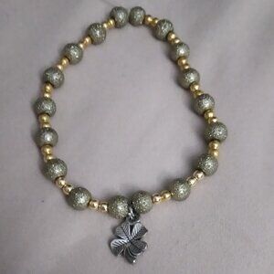 Gold and green beaded bracelet with silver clover charm